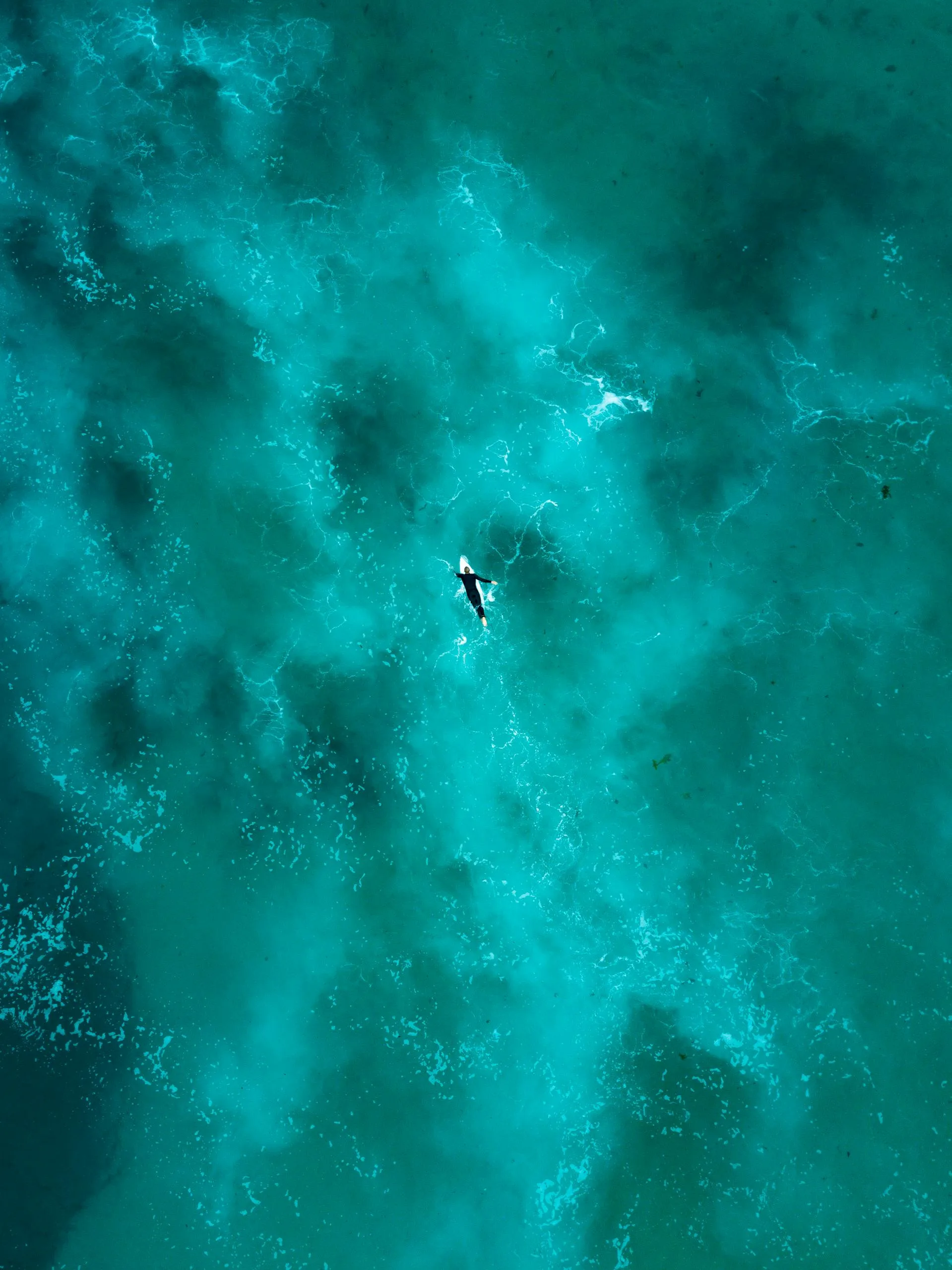 Breathtaking aerial shot of a lone surfer navigating the vibrant turquoise waters